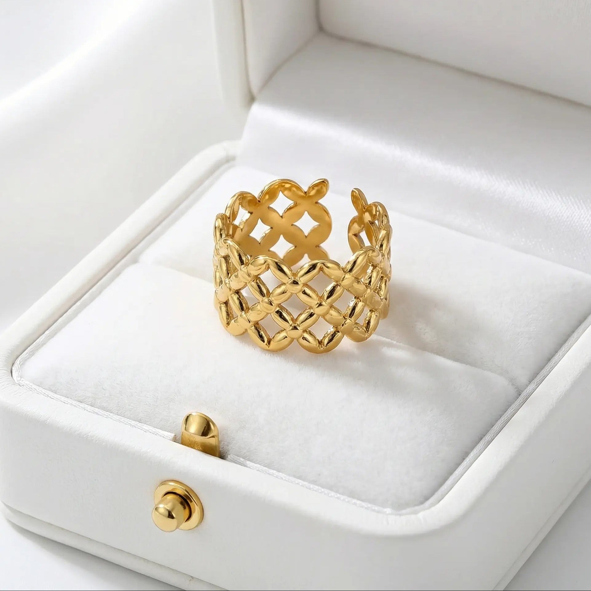 Gold ring with intricate design on a white jewelry box